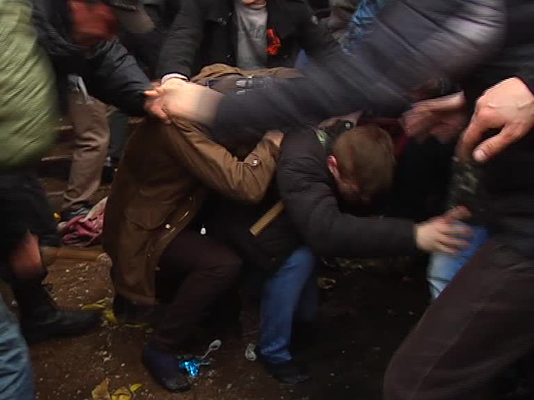 Скриншот видео. Молодых парней мужчина слева бьёт палкой