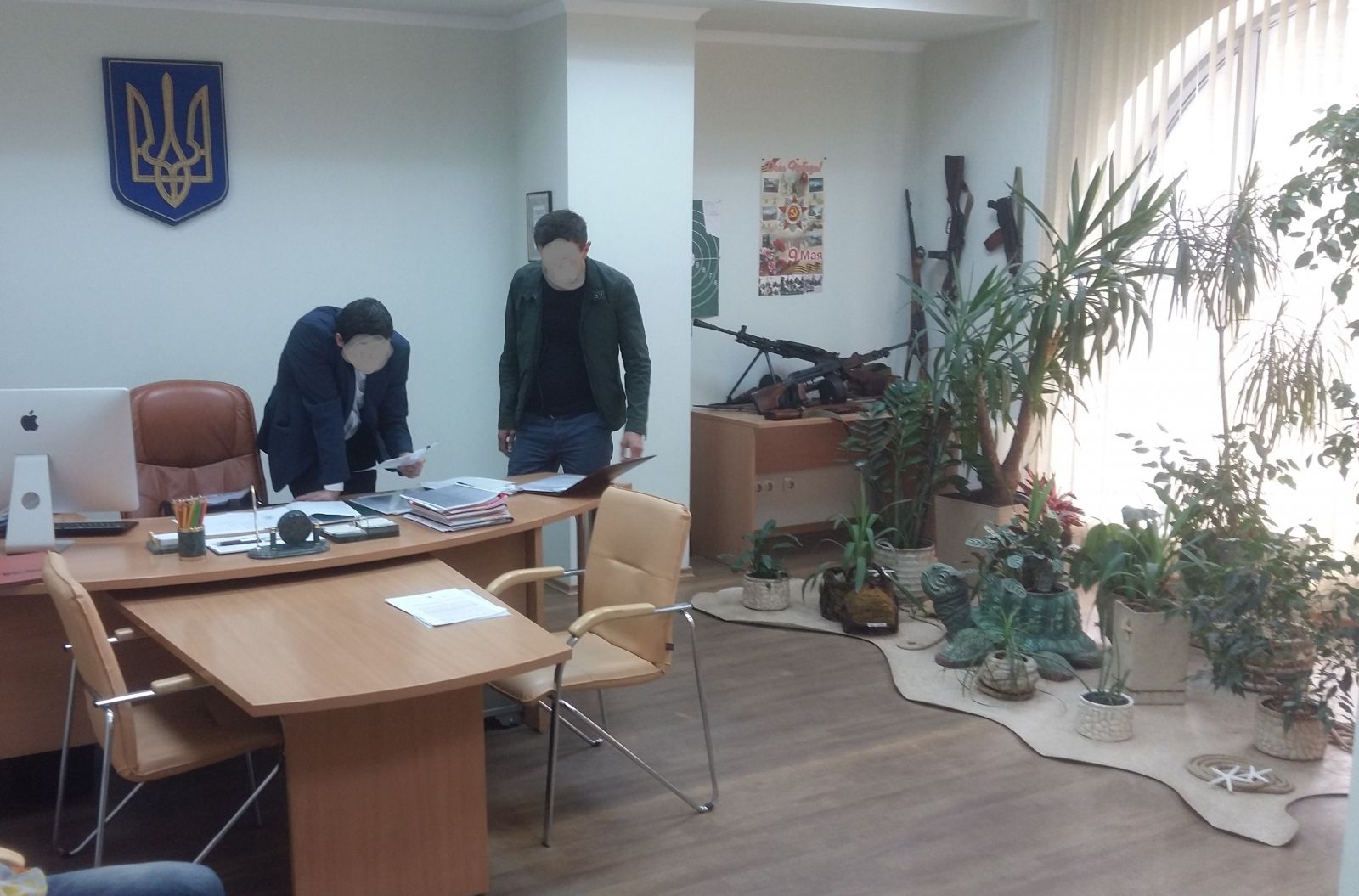 На сайте ГПУ опубликована фото предположительно из кабинета главы Управления Госземагентства в г. Харькове, где возле окна — выставка оружия и зелёный уголок с цветочным горшком в виде черепахи.