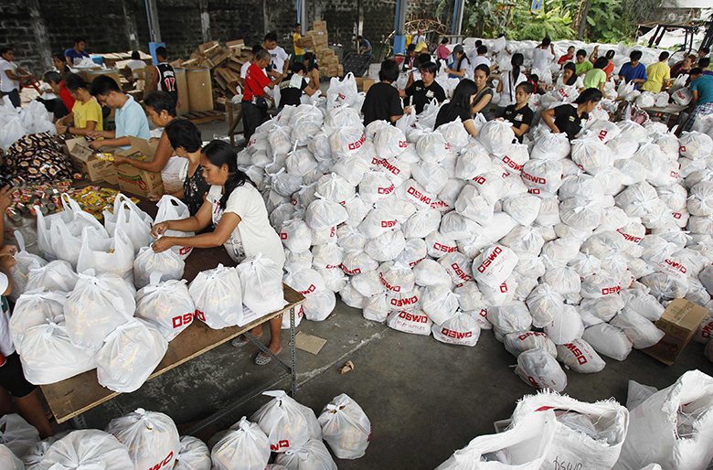 Добровольцы упаковывают продукты внутри правительственного склада в Маниле для отправки в пострадавшие от тайфуна провинции. Фото: Romeo Ranoco/Reuters